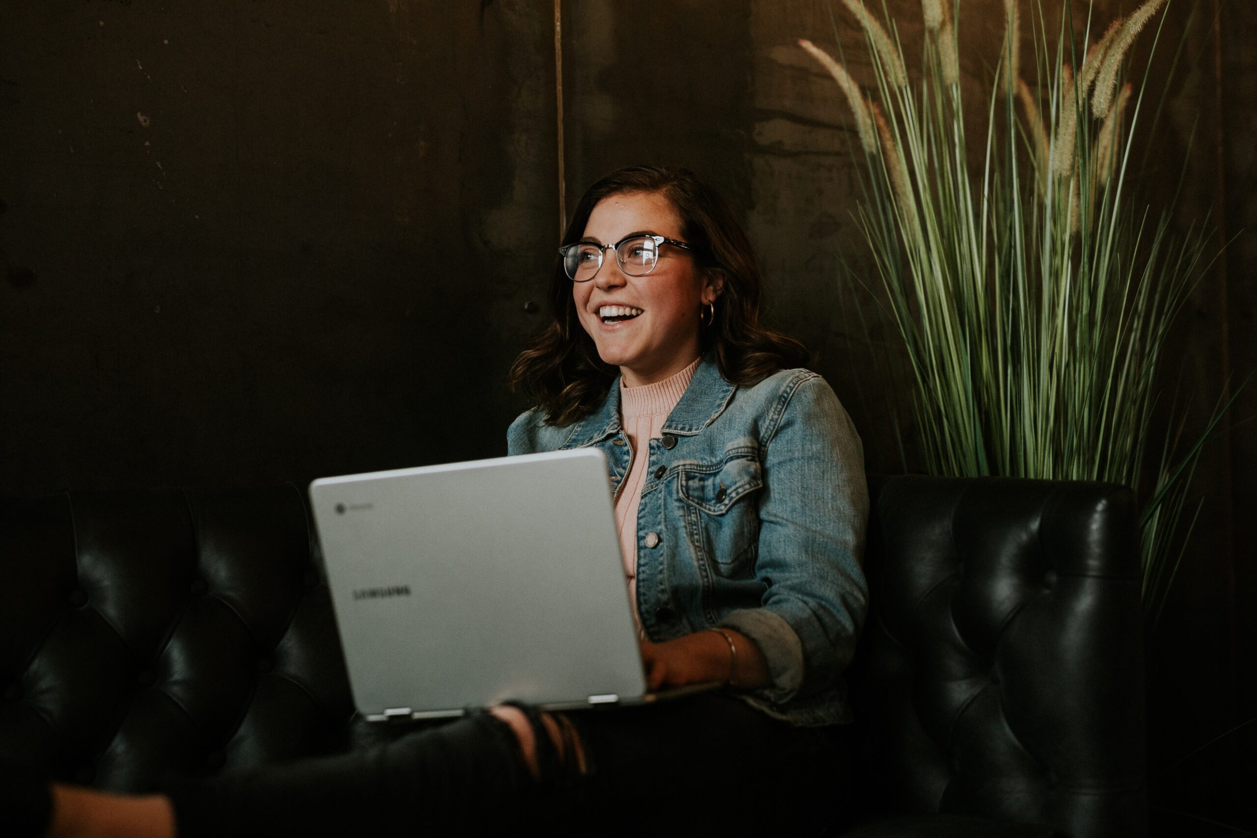 photo of woman with laptop infron of large plant